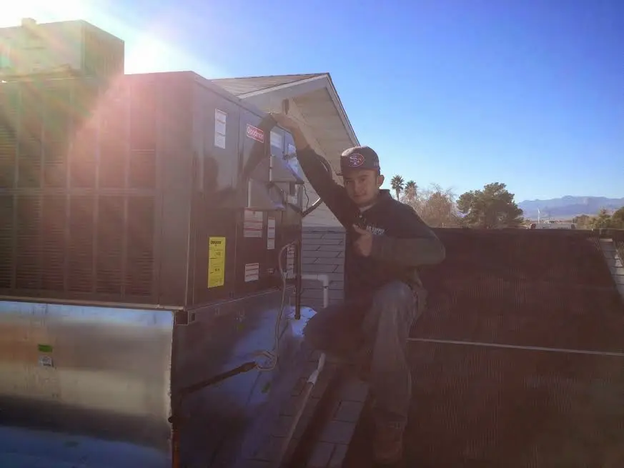 HVAC technician performing HVAC Inspection on a rooftop unit in Gates